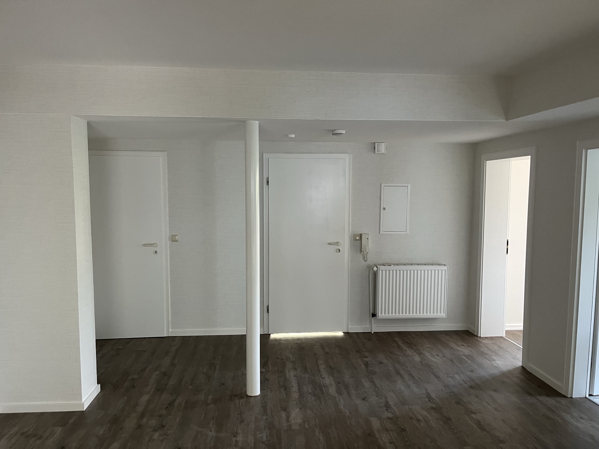 Renovierter Innenraum mit weißen Wänden und dunklem Holzboden