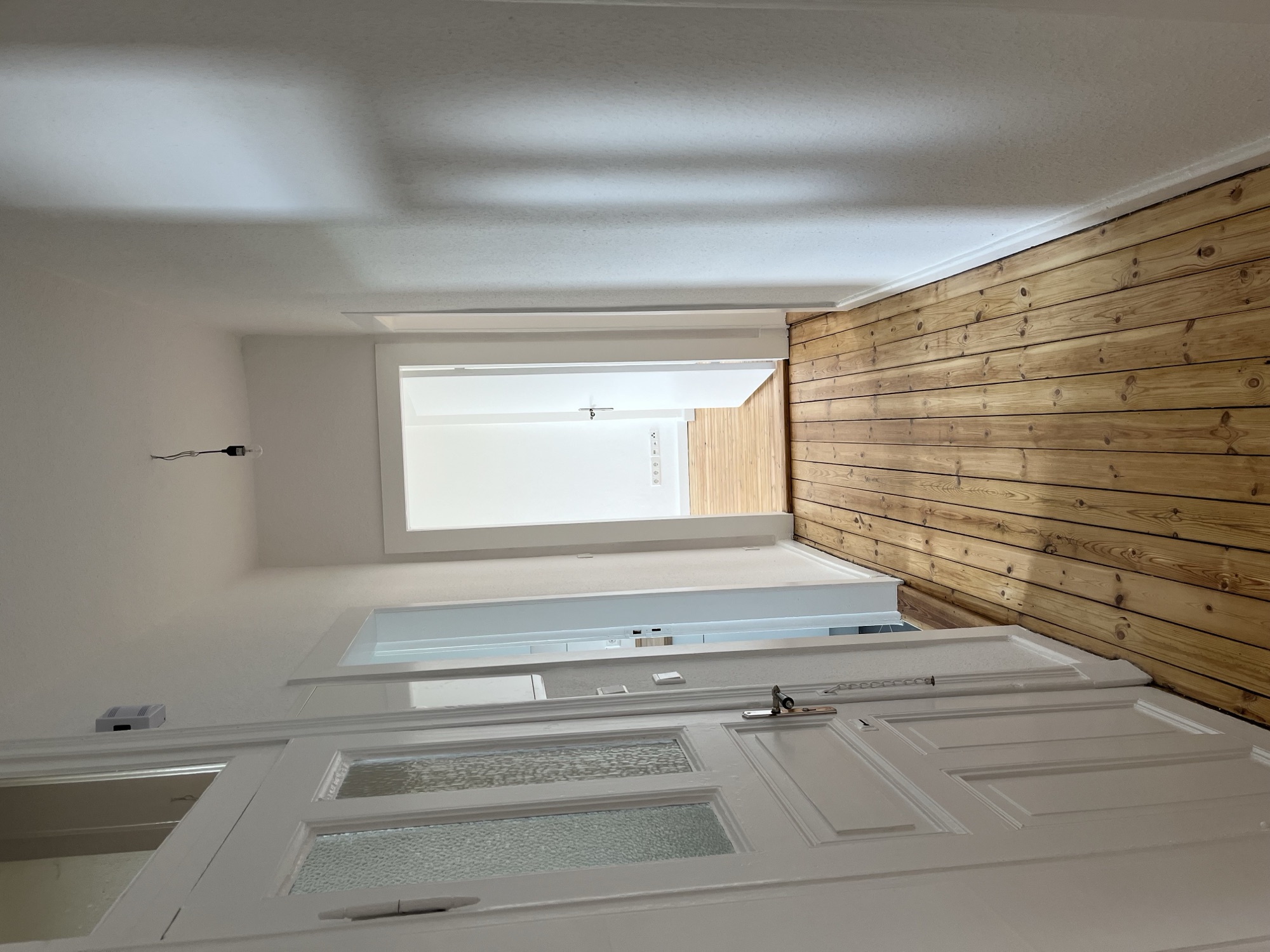 Heller renovierter Flur mit Holzdielenboden und weißen Wänden